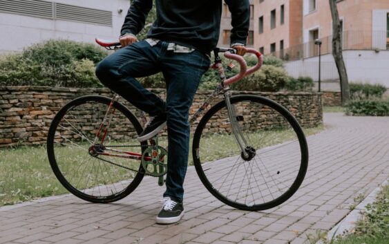 Man in Jeans and Sneakers Posing by Bicycle on Pavement